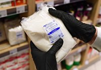 Подсчитана динамика трат россиян на подсолнечное масло и сахар за год - Сельское хозяйство Сотрудник магазина держит в руках пачку с сахаром