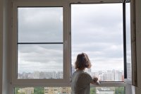 Юрист объяснил, кому опасно продавать свою квартиру - Недвижимость Девушка смотрит в окно в одной из квартир многоэтажного жилого дома по улице Авангардная дом 10 А в Москве, предназначенного для переселения участников программы реновации.