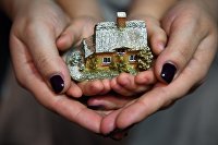 Составлен рейтинг регионов по доле затрат семей на "коммуналку" - Регионы Женщина с ребенком держат макет дома