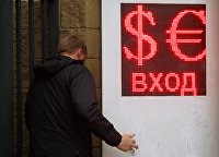 Курс доллара корректируется после снижения на данных об инфляции - Валюта Мужчина у входа в обменный пункт валют в Москве